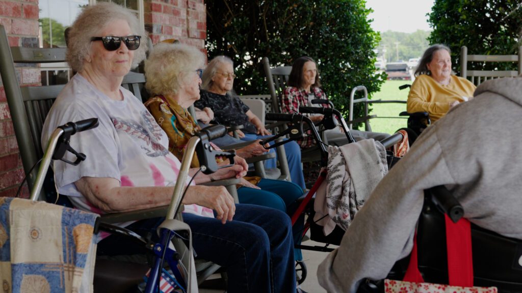 A group of women at a skilled nursing facility sitting on the front porch