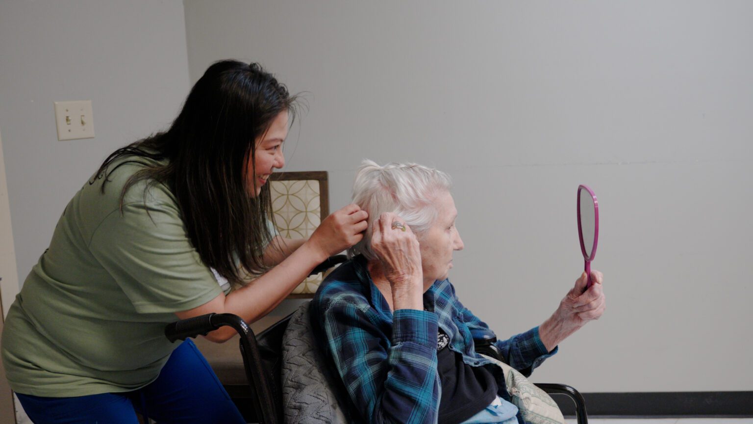 A stylist works on a resident at a skilled nursing facility's hair in the provided salon
