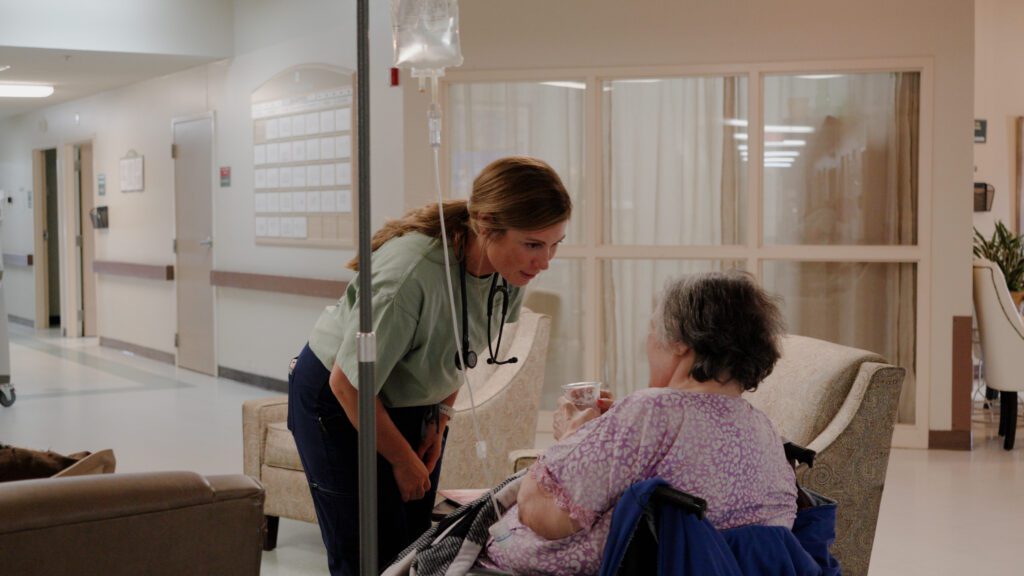A nurse smiling and talking to a resident at a skilled nursing facility