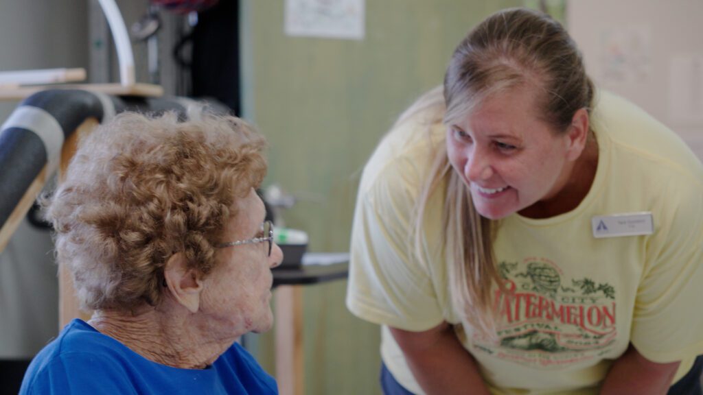 A nurse smiles at a resident at a skilled nursing facility